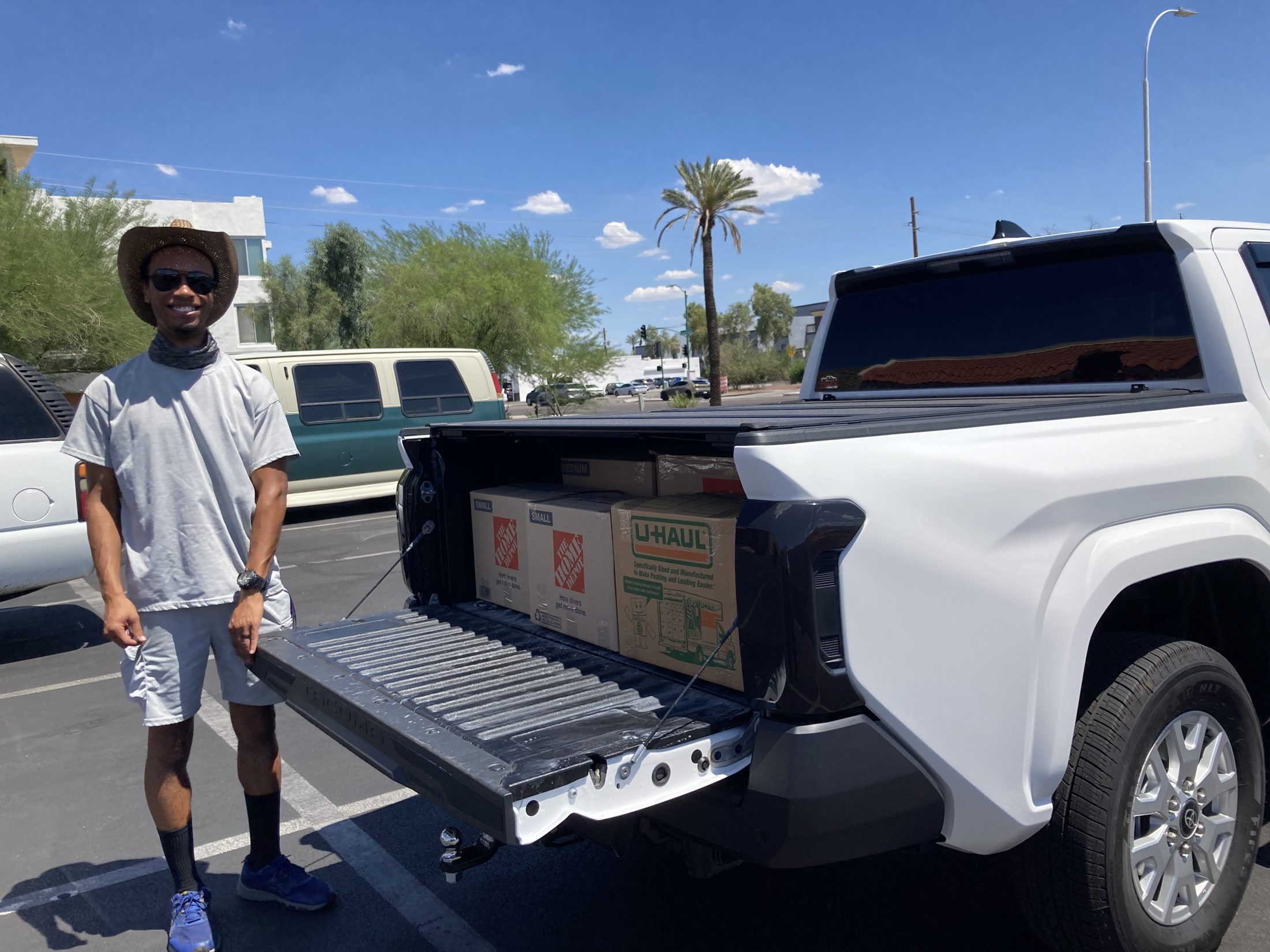 Dom from Reuben's Hauling LLC beside a pickup truck loaded with moving boxes, ready for a job.